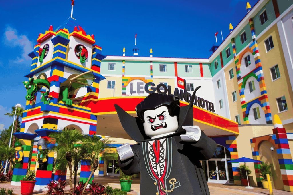 Colorful LEGOLAND Hotel exterior with a large LEGO vampire statue in front and palm plants nearby.